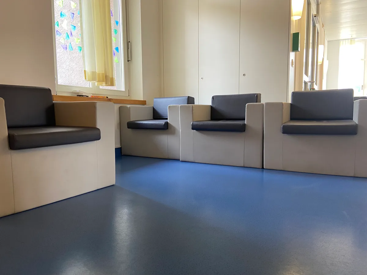 Selbst der Aufenthaltsbereich ist auf die Sicherheit ausgerichtet. Diese Sessel sind kaum zu bewegen. Sicherheitsstühle in einem Raum.